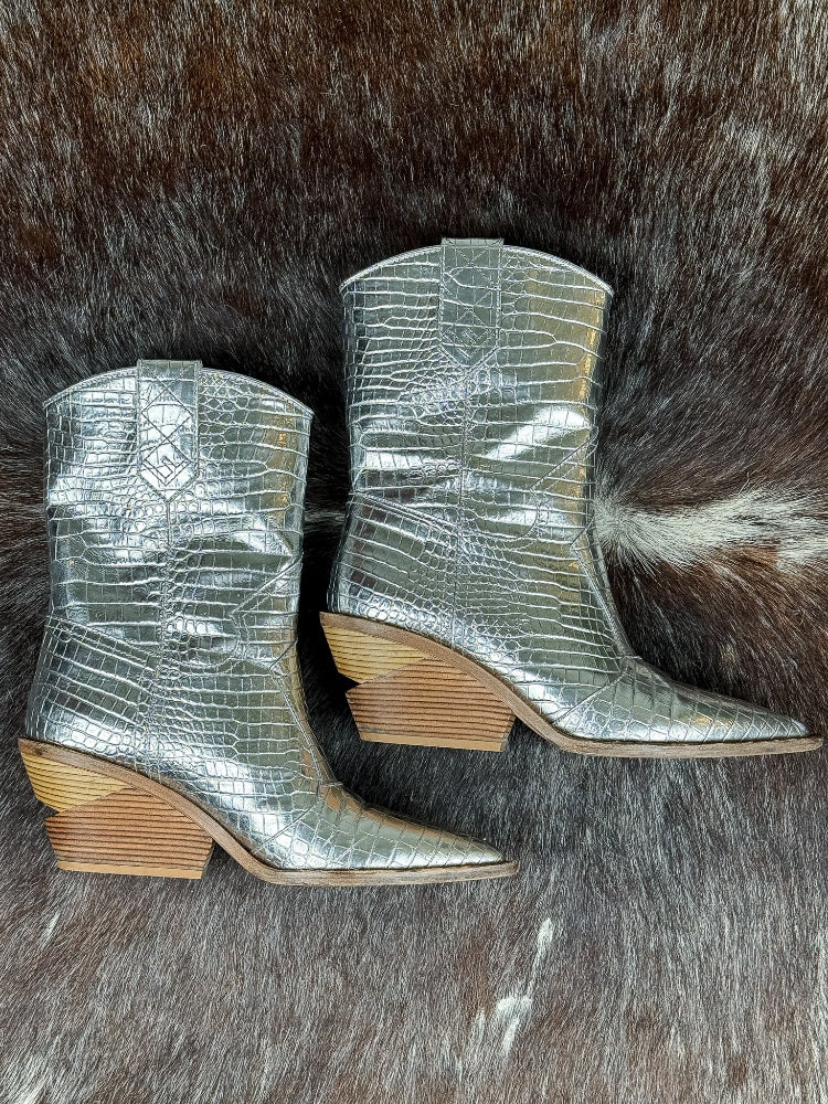 Silver metallic cowboy boots with wooden soles on a fur surface